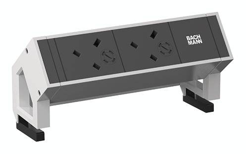 Module d'alimentation noir, rectangulaire, avec deux prises électriques et logo BACHMANN, monté sur un cadre blanc incliné.