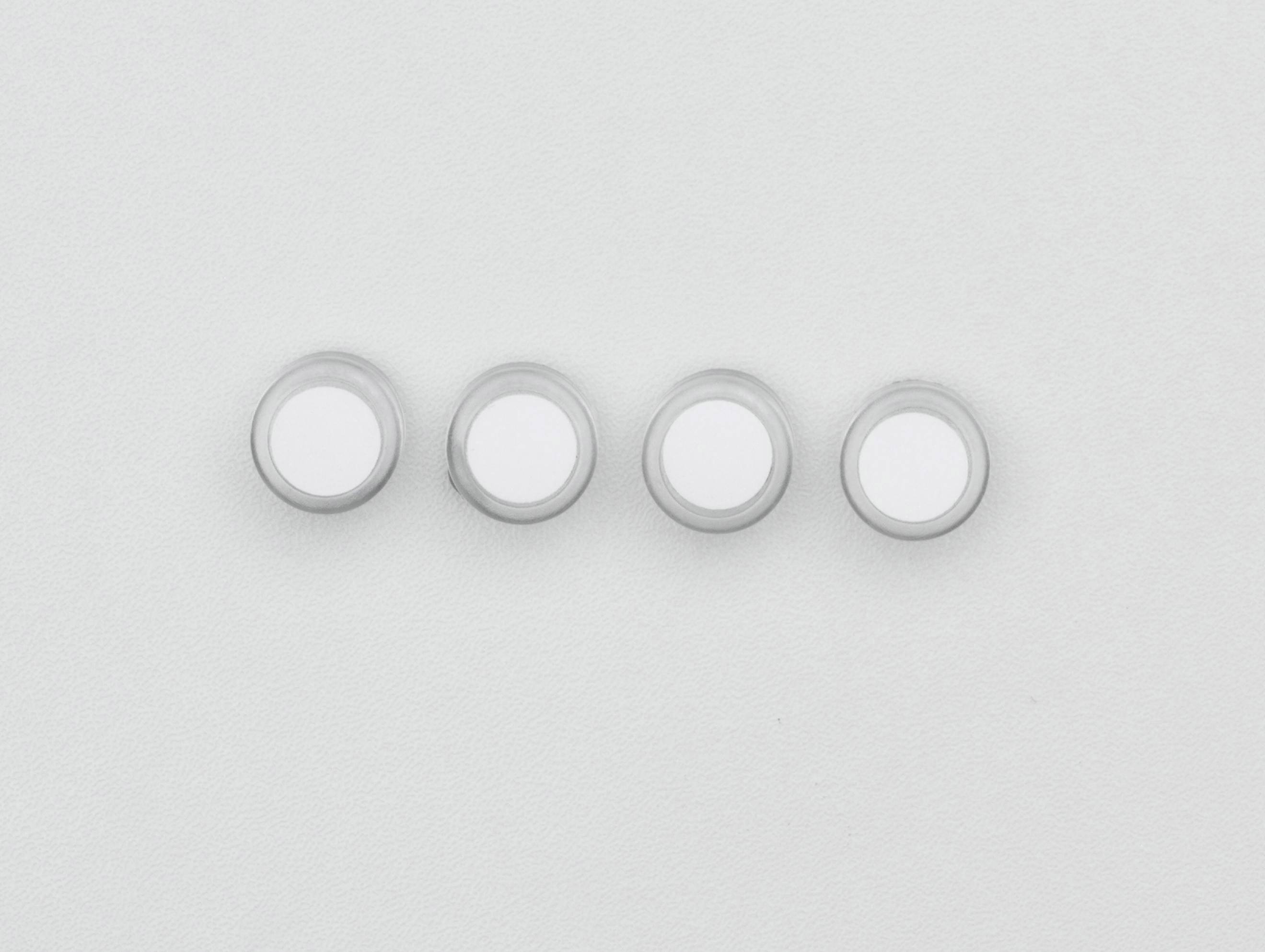 Quatre boutons blancs, identiques et ronds, alignés en rang sur un fond gris clair.