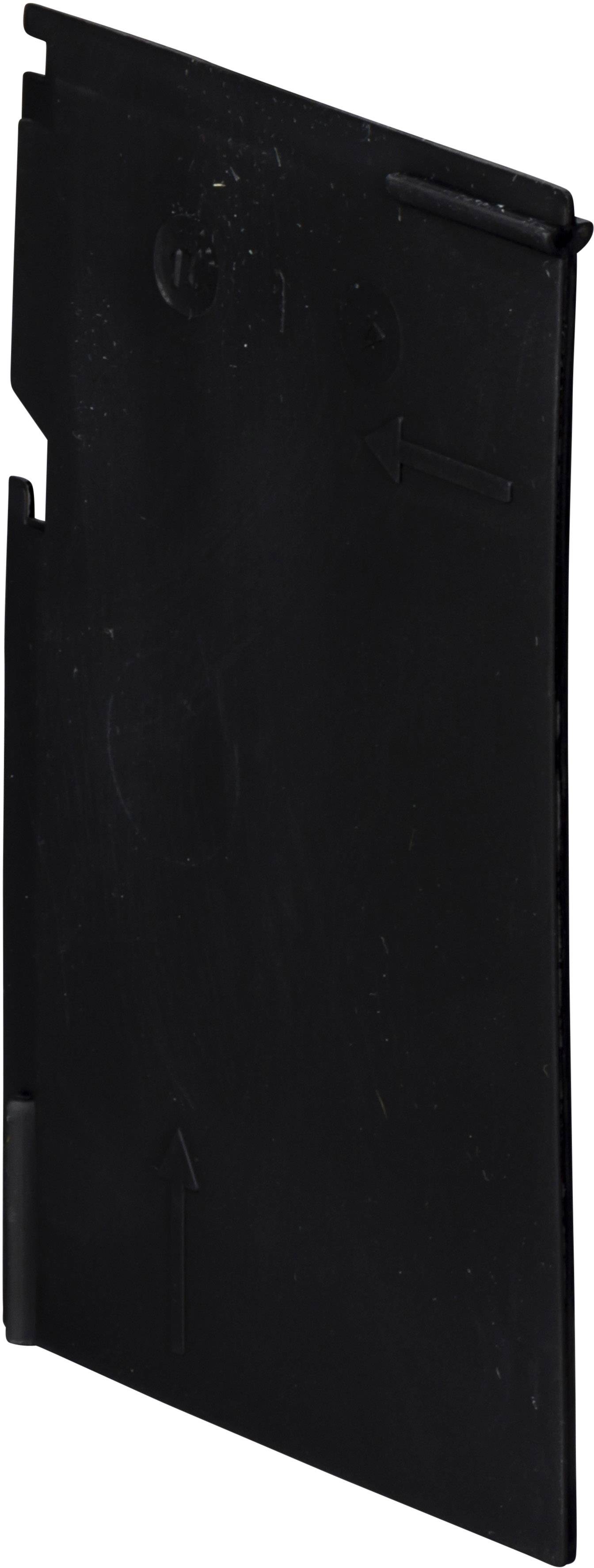 Pièce en plastique noir, probablement un couvercle ou un élément de fermeture, avec des flèches de direction sur la surface.