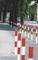 Des poteaux rouges et blancs le long d'un trottoir dans un environnement urbain, servant de barrière ou de délimitation de chemin.