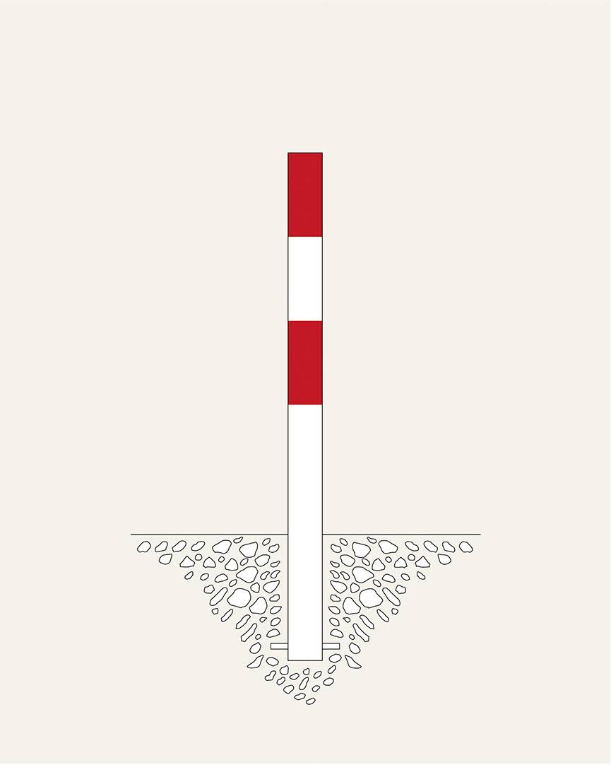 Un poteau rayé rouge et blanc est partiellement enfoncé dans le sol, entouré de gravier.