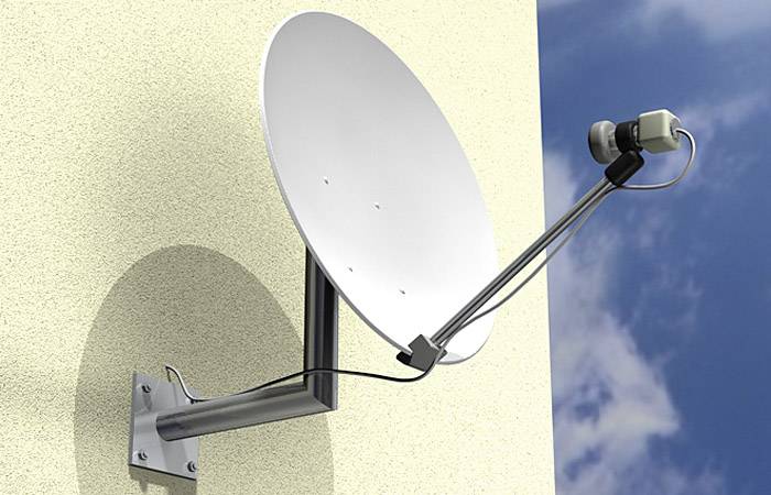 Parabole fixée à un mur jaune, orientée pour recevoir des signaux satellitaires. Ciel bleu en arrière-plan.