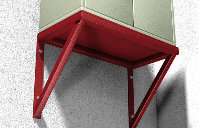 Un cadre métallique rouge soutient une armoire grise contre un mur texturé, probablement dans un environnement industriel.