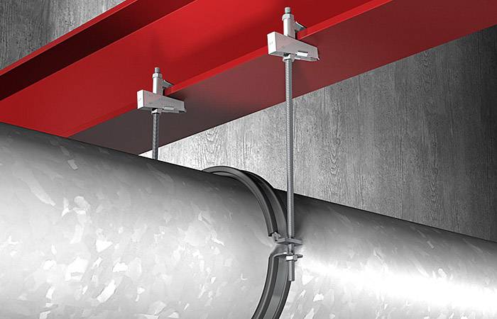 Un tube métallique est fixé à l'aide de deux supports sur une poutre en acier rouge, illustrant la suspension dans un environnement industriel.