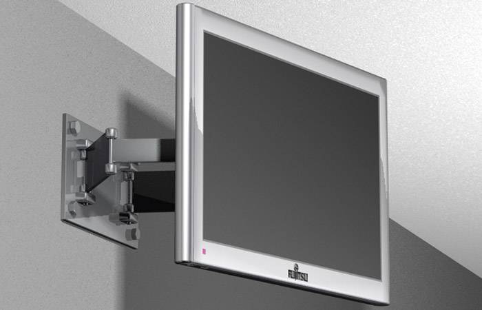 Écran plat fixé sur un support mural ajustable, installé dans une pièce aux murs gris.