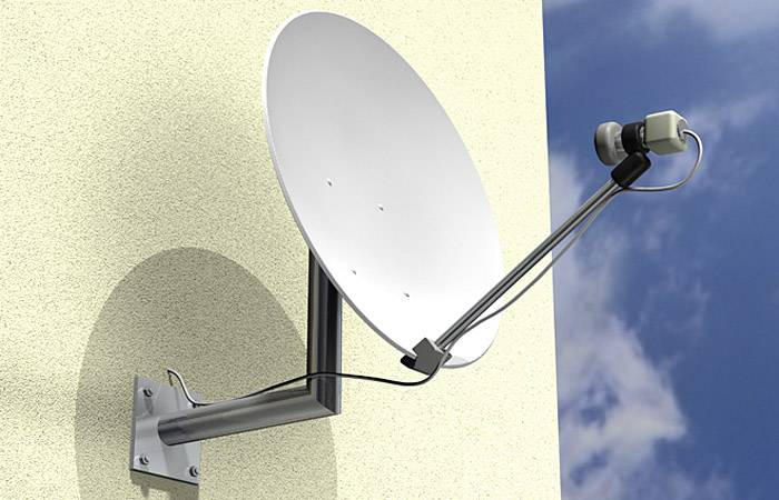 Parabole satellite fixée sur un mur de maison, orientée vers le ciel.