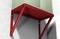 Étagère métallique rouge contre un mur, supportant une armoire grise. Les supports de montage sont absents, détails de l'armoire mis en valeur, accent sur la structure.