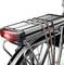 Un vélo argenté avec un porte-bagages noir et un feu arrière rouge, maintenu par des sangles élastiques.
