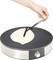 Une main répartit de la pâte liquide sur une poêle électrique ronde à crêpes à l'aide d'un répartiteur de pâte à crêpes.