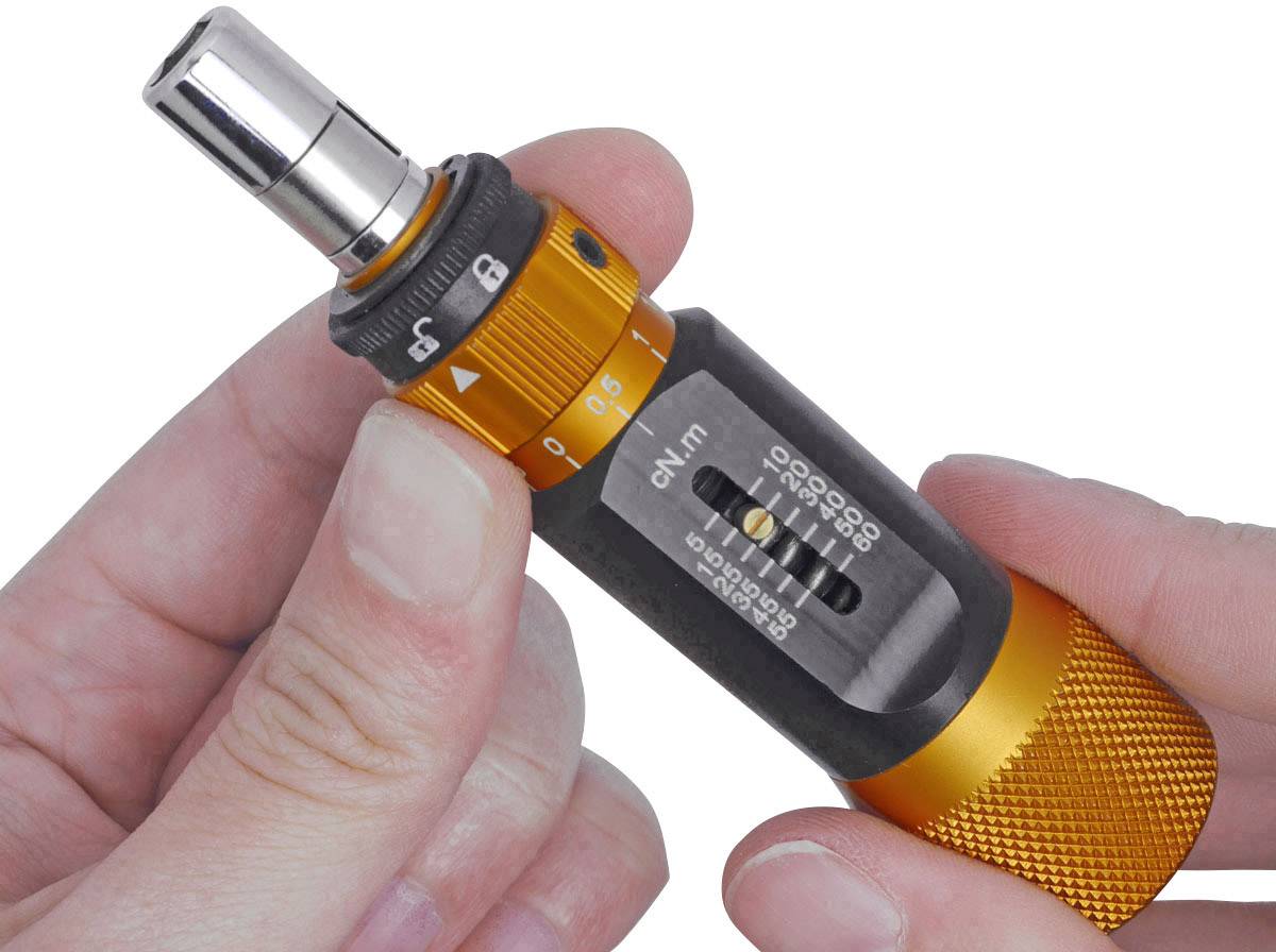 Une main tient un outil de couple de serrage orange avec un indicateur d'échelle, utilisé pour des réglages précis du couple de serrage des vis.
