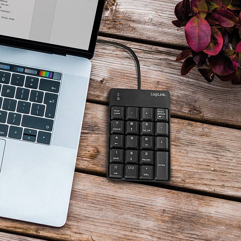 Un ordinateur portable avec le couvercle ouvert affiche un tableau sur l'écran. À côté se trouve un pavé numérique externe posé sur une table en bois.