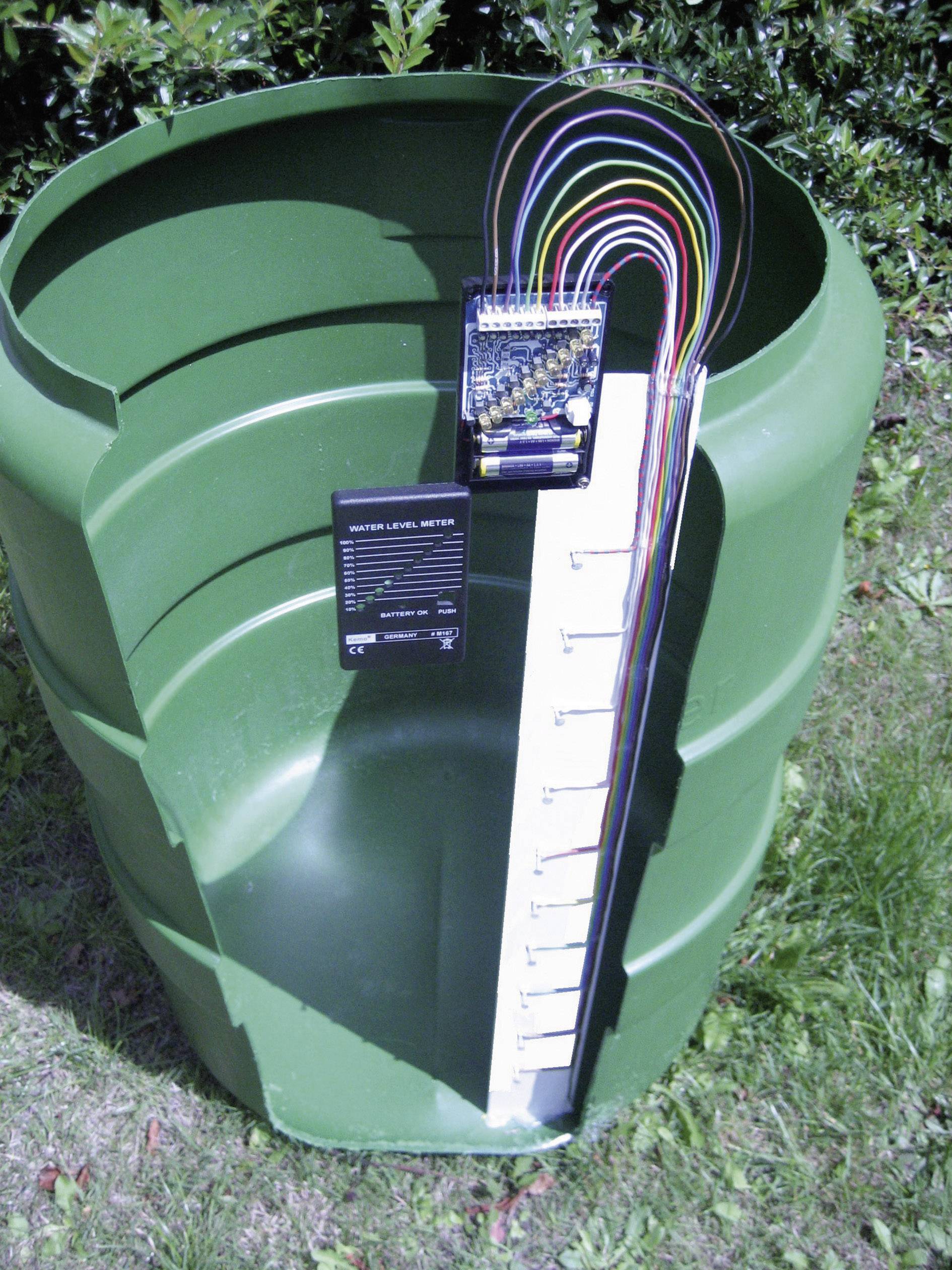 Un réservoir d'eau vert avec un système de câblage connecté et des capteurs de mesure du niveau d'eau. Une échelle indique le niveau de remplissage.