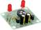 Un circuit électronique vert avec deux LED rouges, des résistances et des condensateurs visible sur une carte de circuit imprimé.