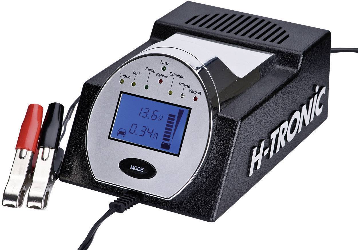 Chargeur de batterie avec affichage numérique indiquant '13,6V' et le niveau de charge. Deux bornes de couleur rouge et noire sont connectées.