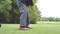 Une personne frappe une balle de golf sur un terrain de golf avec un club de golf. En arrière-plan, on peut voir de l'herbe et des arbres.