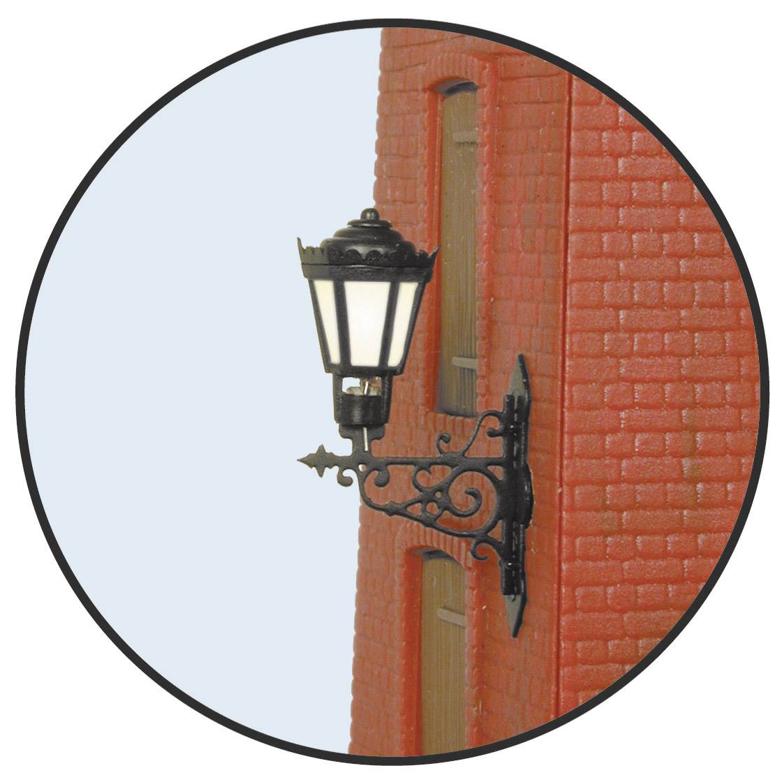 Un ornement mural décoratif représente une lanterne antique contre un mur de briques rouges.