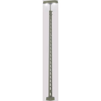 Un lampadaire gris élevé avec un socle rectangulaire et plusieurs ouvertures carrées le long du mât, illuminé.