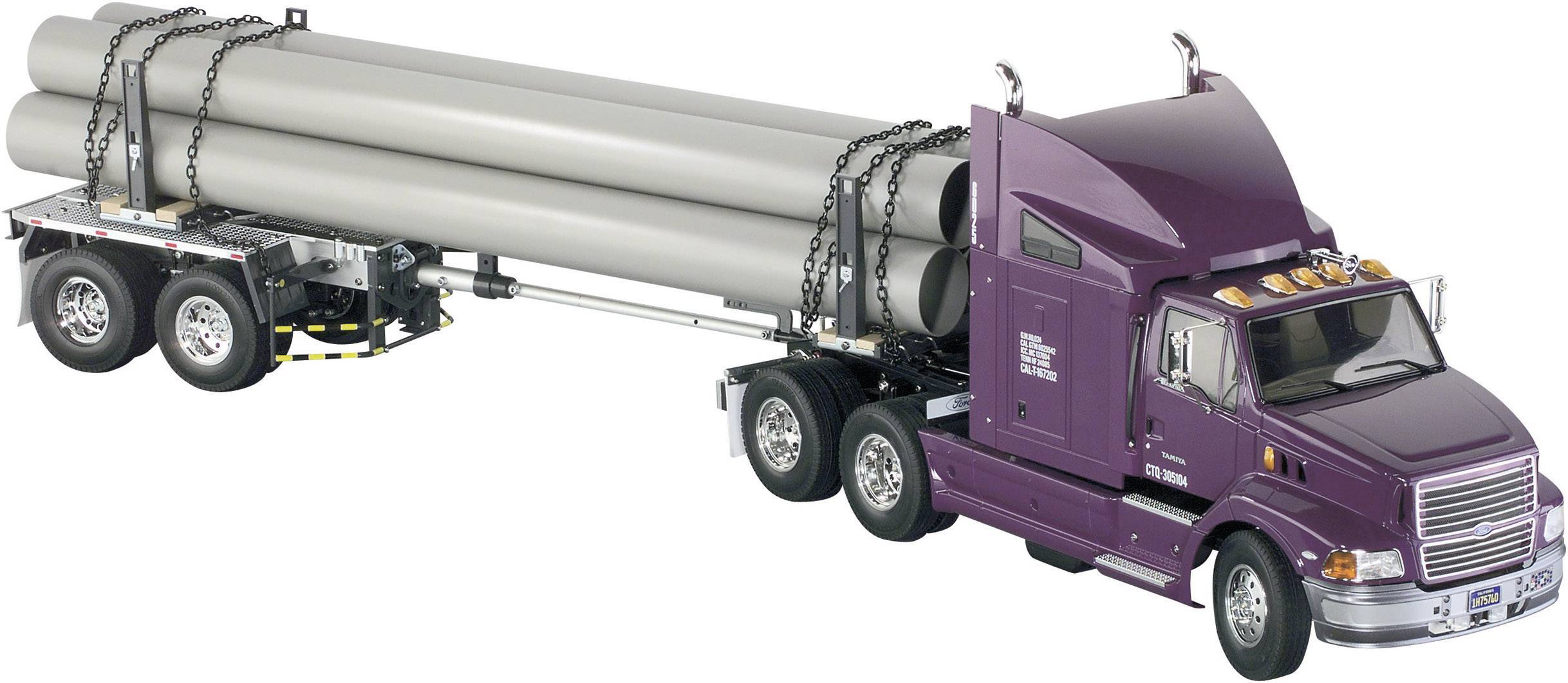 Un camion avec semi-remorque transporte de longs tubes gris. La remorque a trois essieux, et les tubes sont arrimés avec des chaînes.