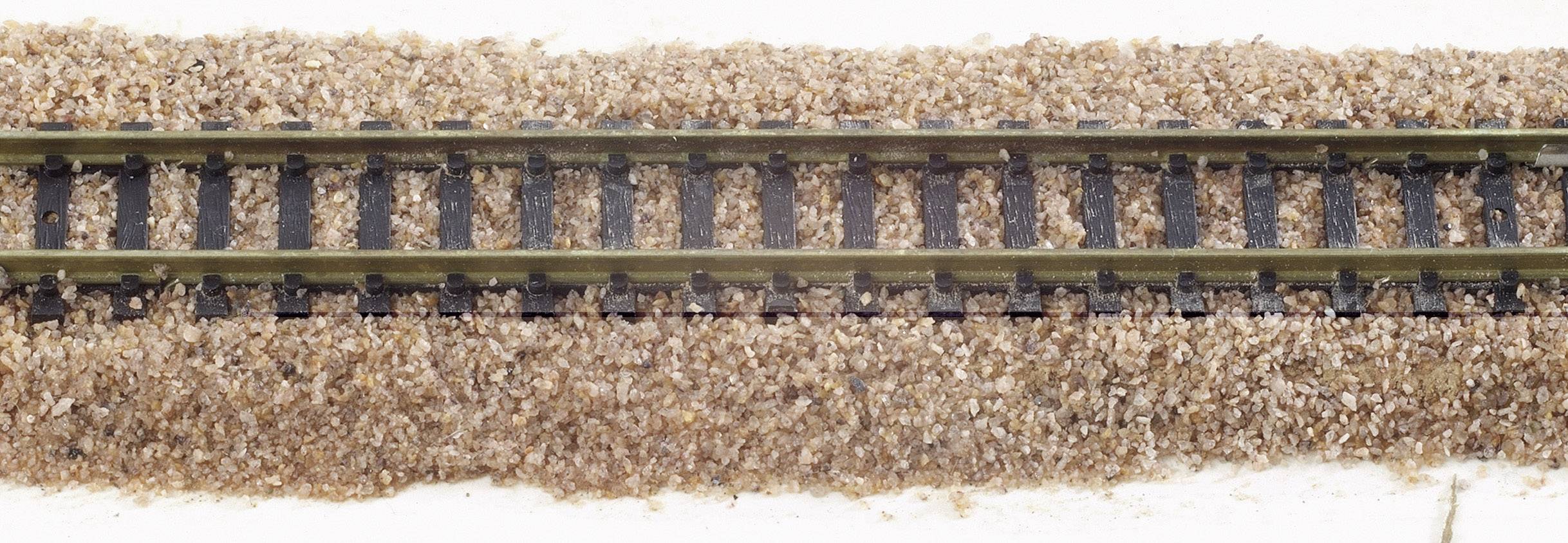 Un tronçon de voie ferrée avec ballast. Des rails étroits traversent horizontalement le centre de l'image.