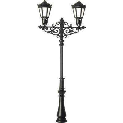 Un lampadaire décoratif antique en métal avec deux lanternes brillant intensément. Il est placé devant un fond neutre.