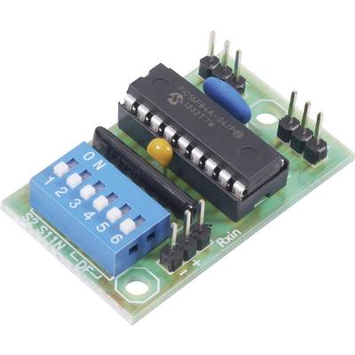 Circuit électronique avec une puce IC noire, un interrupteur DIP bleu et plusieurs broches sur une carte de circuit imprimé verte.