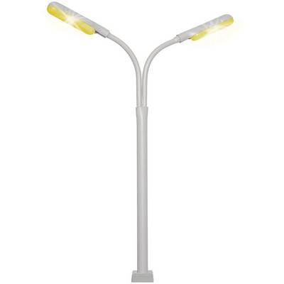 Un lampadaire moderne avec deux luminaires inclinés vers l'extérieur, émettant une lumière jaune, se dresse devant un fond blanc.