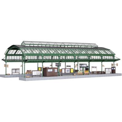 Un modèle d'une gare historique avec une verrière verte, plusieurs quais et des panneaux. Il est conçu avec un grand souci du détail.