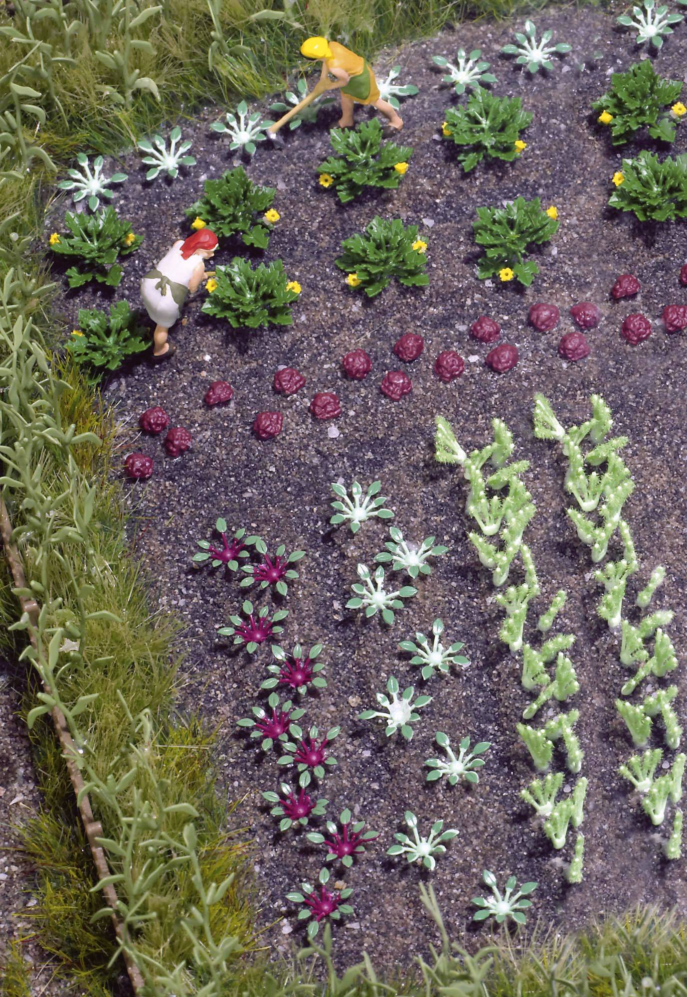 Deux petites figurines travaillent dans un potager. Différentes variétés de plantes sont visibles dans des rangées bien ordonnées.