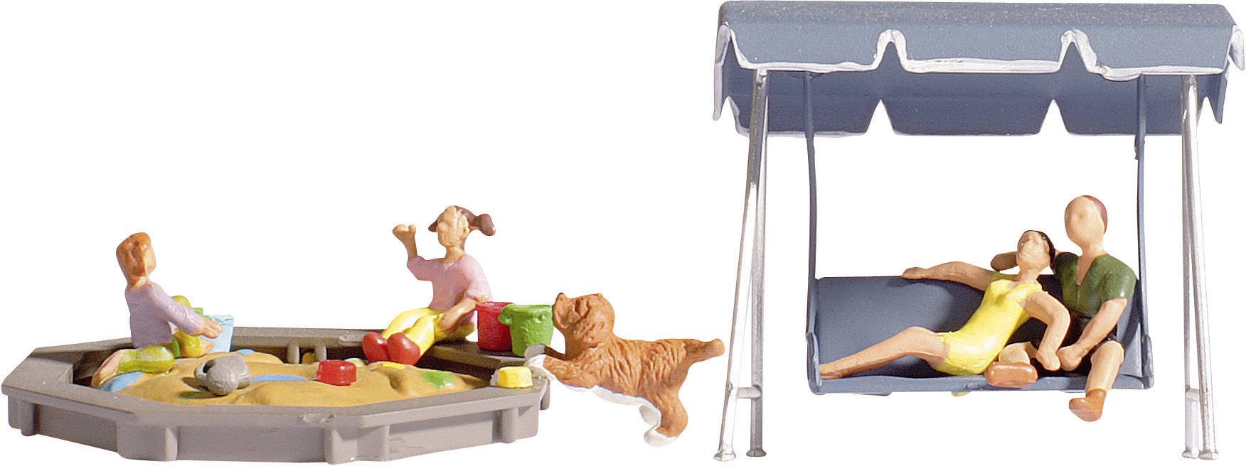 De petites figurines sont assises dans le bac à sable et un couple se détend sur un banc à bascule à côté, tandis qu'un chien joue.