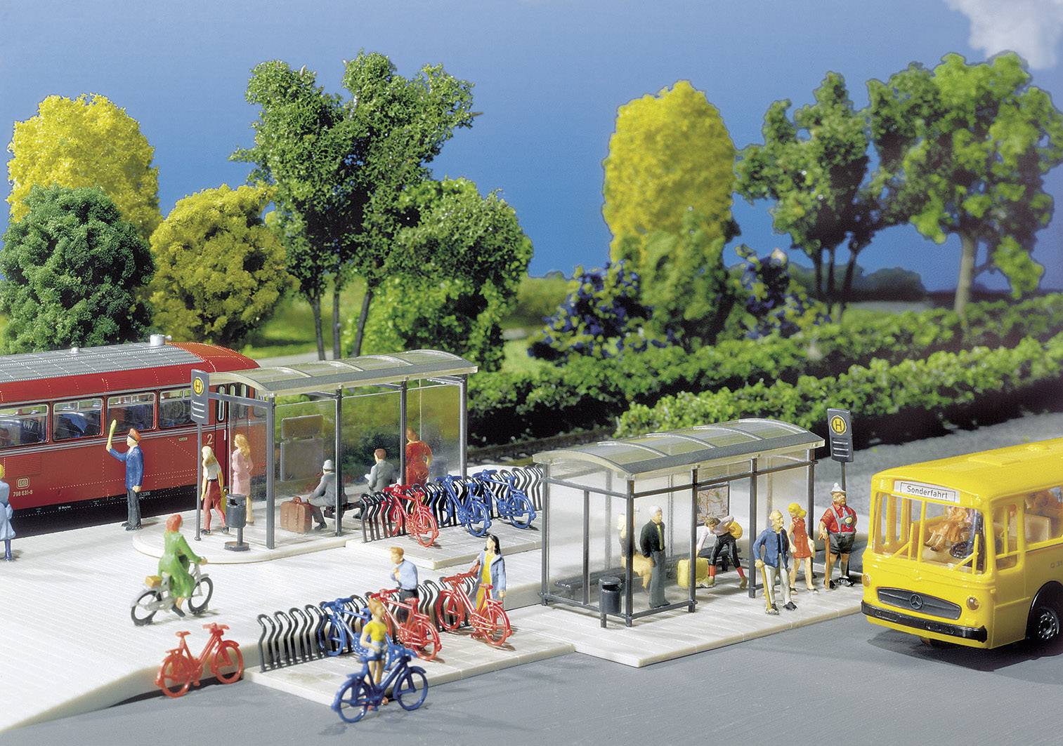 Un diorama représente une gare animée de bus et de vélos. Des personnes attendent des bus, rangent leurs vélos et se déplacent çà et là.
