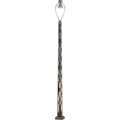 Un lampadaire en fer forgé à structure de grille ouverte et délicate. Une ampoule est placée en haut, protégée par une cage.