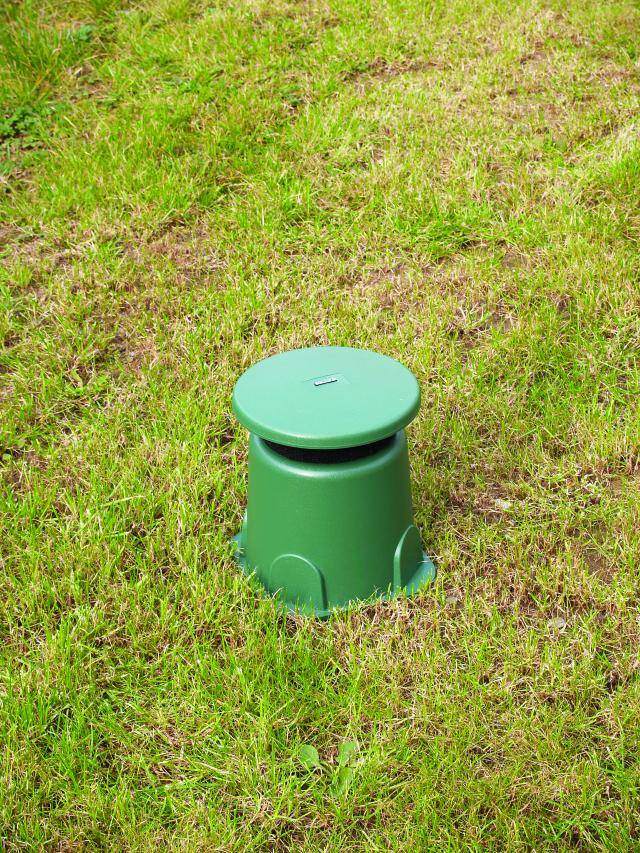 Champignon aérateur vert installé sur une pelouse pour l'aération du sol.