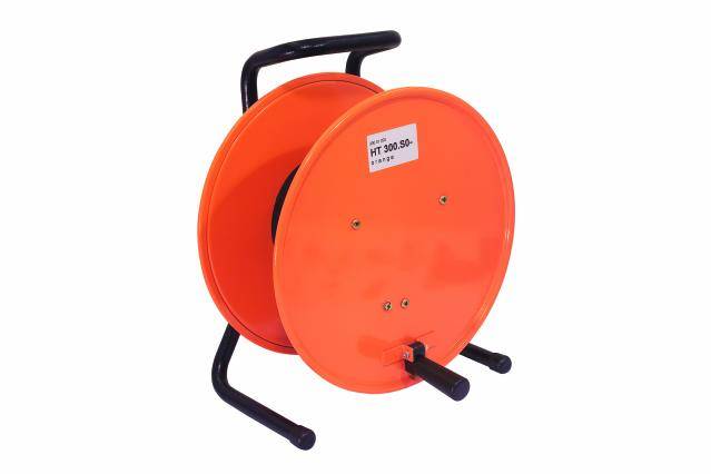 Une bobine de câble orange vide avec une poignée et deux pieds de support, placée sur une surface.