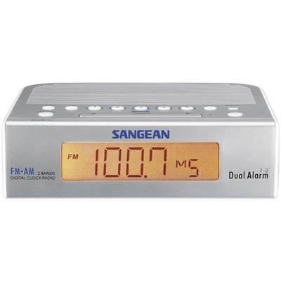 Un réveil radio numérique de Sangean affiche 'FM 100,7 MHz' sur un écran orange. Des touches de fonction sont visibles en haut de l'appareil.