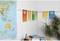 Mur avec des affiches colorées dans un bureau ; à côté, une carte du monde sur un bureau avec des livres et une plante.