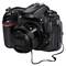 Appareil photo numérique avec objectif interchangeable, de nombreux boutons et molettes sur le dessus. Bouchon d'objectif avec cordon de fixation.