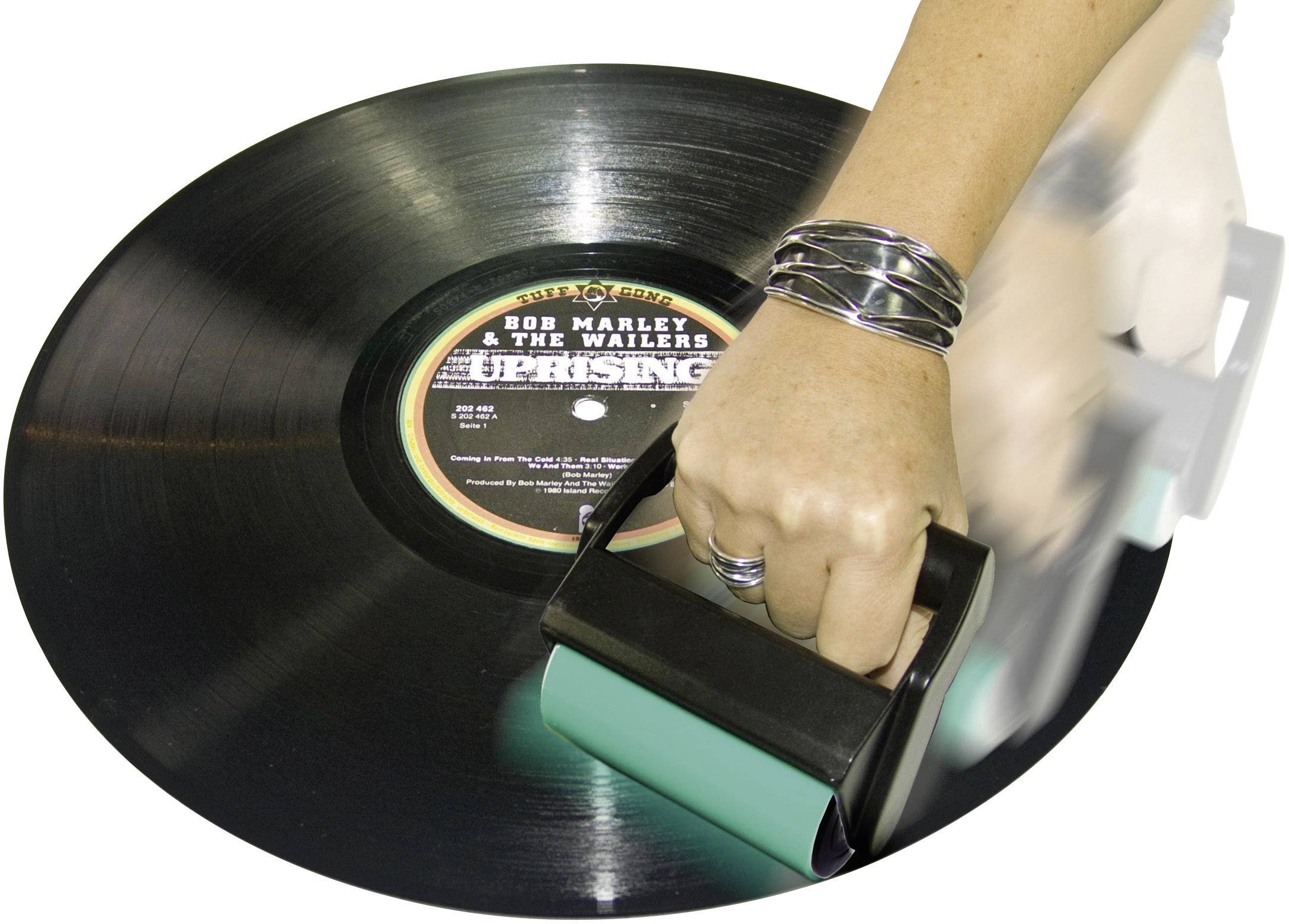 Une main nettoie un disque vinyle avec une brosse. Sur la pochette de l'album, on peut lire « Bob Marley & The Wailers - Uprising ».
