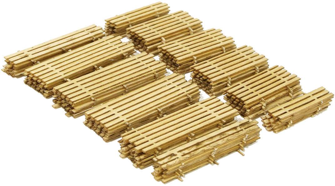 Plusieurs fagots de fines baguettes de bois, disposés de manière uniforme en rangées sur une surface blanche.