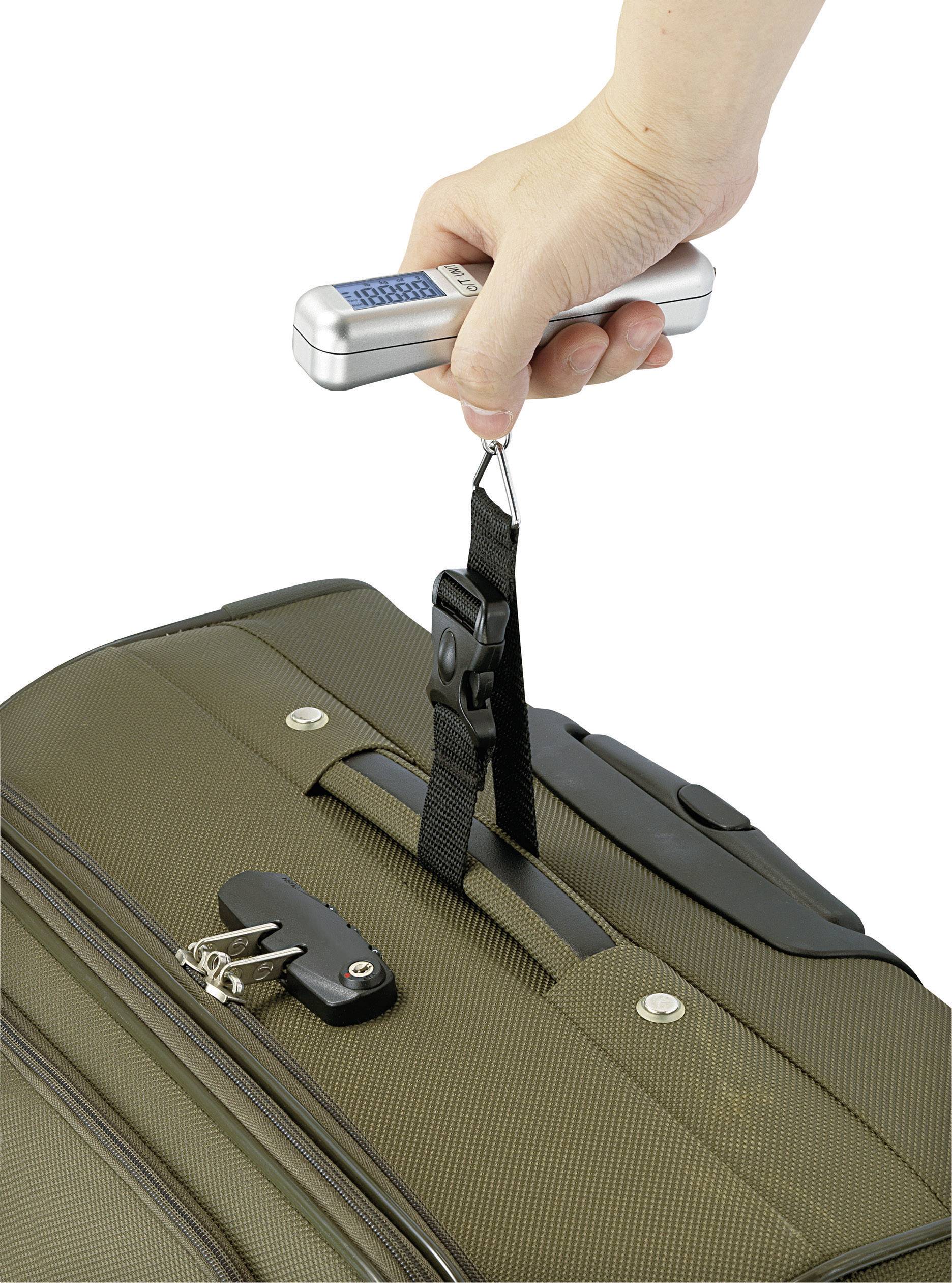 Une main tient une balance portable attachée à un bagage pour en mesurer le poids.