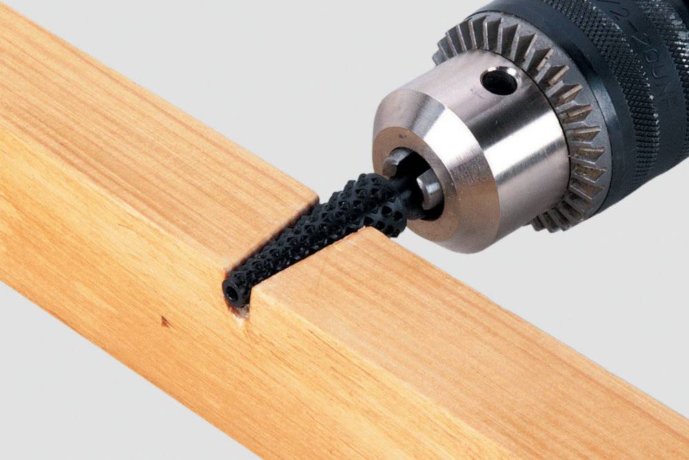 Une perceuse travaille un morceau de bois avec un embout spécial qui enlève le matériau de manière précise.