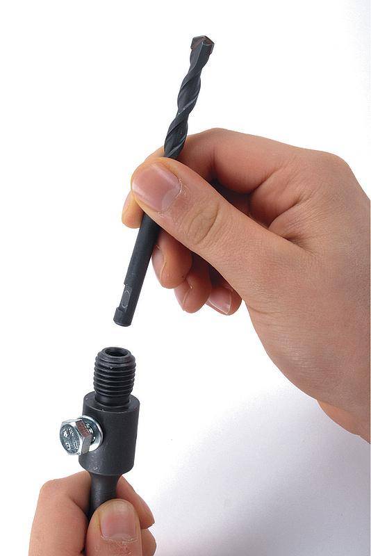 Des mains tiennent une perceuse au-dessus d'un support métallique avec une vis, prêtes à percer.