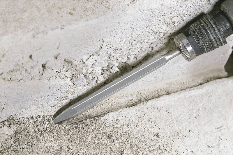 Un burin fiché dans une surface en béton indique le forage ou le travail du béton ou de la pierre.