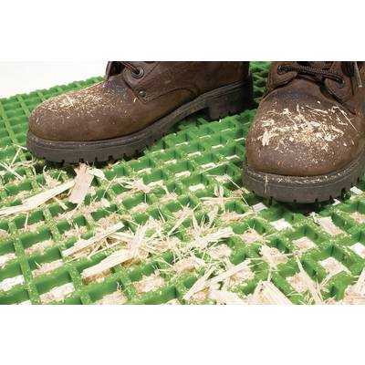 Une paire de bottes brunes est posée sur un tapis de grille vert, recouvert de copeaux de bois.