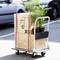 Un chariot de transport chargé de cartons et de plantes est stationné sur un parking. Les cartons sont marqués d'icônes et de la mention 'XS'.
