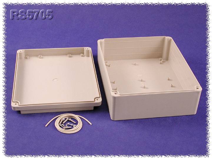 Boîtier rectangulaire en plastique gris ouvert sur un fond lilas, avec son couvercle à côté et un câble. Accessoires à assembler.