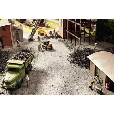 Une scène miniature montre des ouvriers chargeant du charbon sur des camions et des machines dans un paysage industriel.