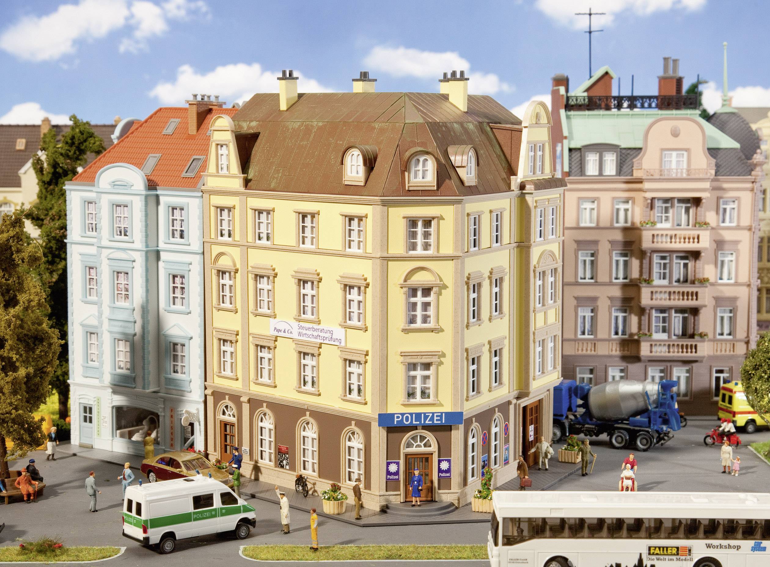 Une scène de rue animée représente une ville miniature avec un poste de police au centre, entouré de bâtiments et de véhicules colorés.