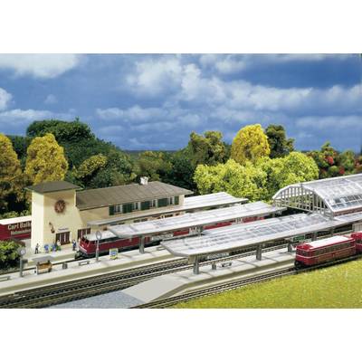 Modèle réduit d'une gare avec deux trains sur les voies, entouré d'arbres. Des personnes attendent sur le quai.