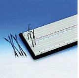 Un support de breadboard vide est positionné en angle sur une surface. À côté se trouvent plusieurs ponts de câblage détachés.