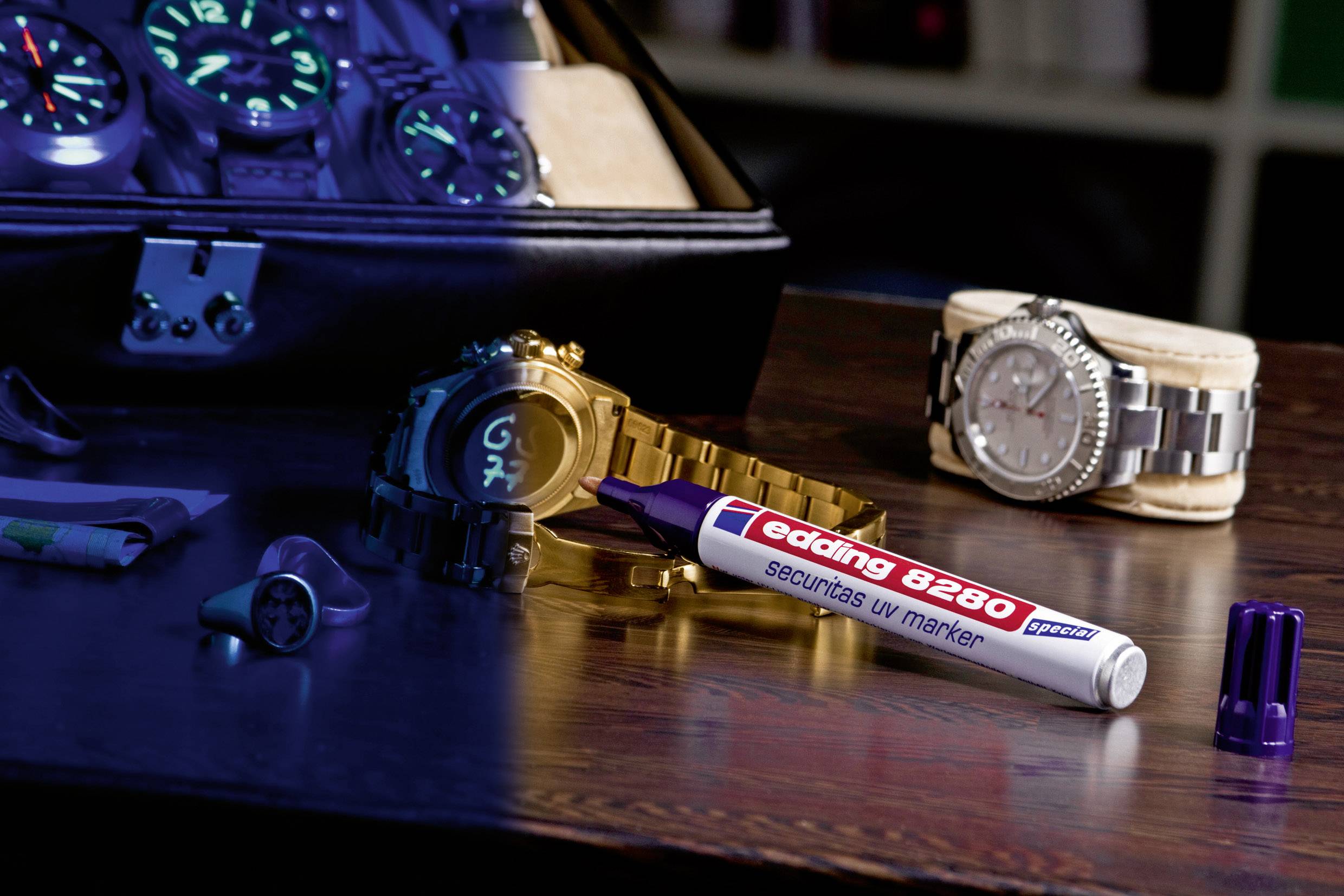 Un marqueur UV est posé sur une table près de montres-bracelets. La moitié gauche de l'image est illuminée en bleu et montre des marquages lumineux.